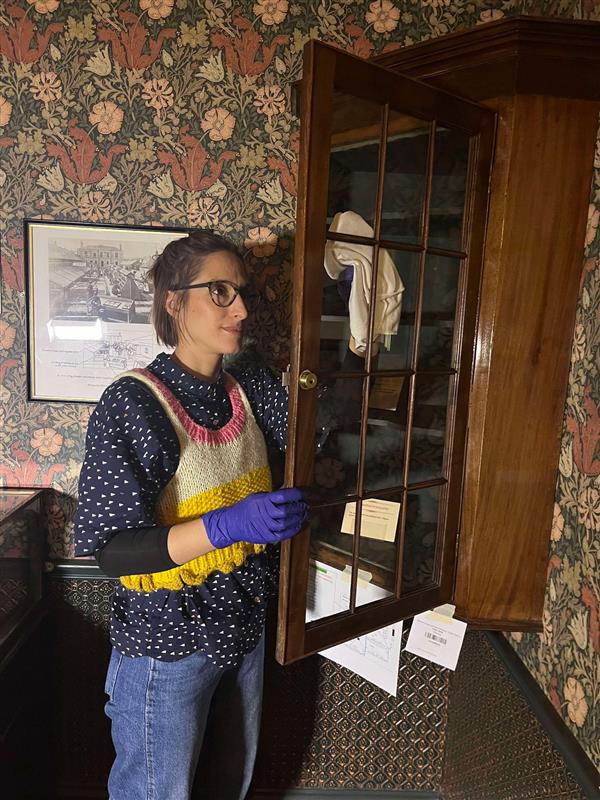 Vanessa cleaning the glass of a corner object showcase.