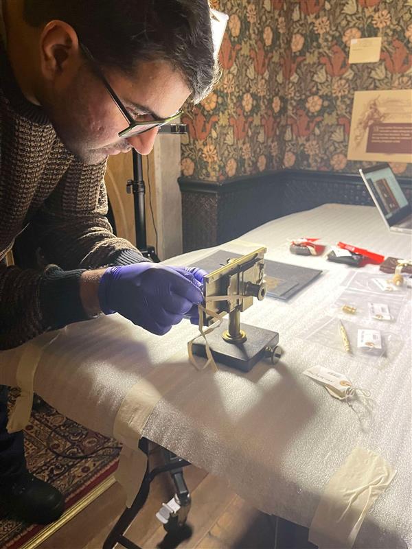 Saquib wears blue nitrile gloves to delicately handle an old camera.