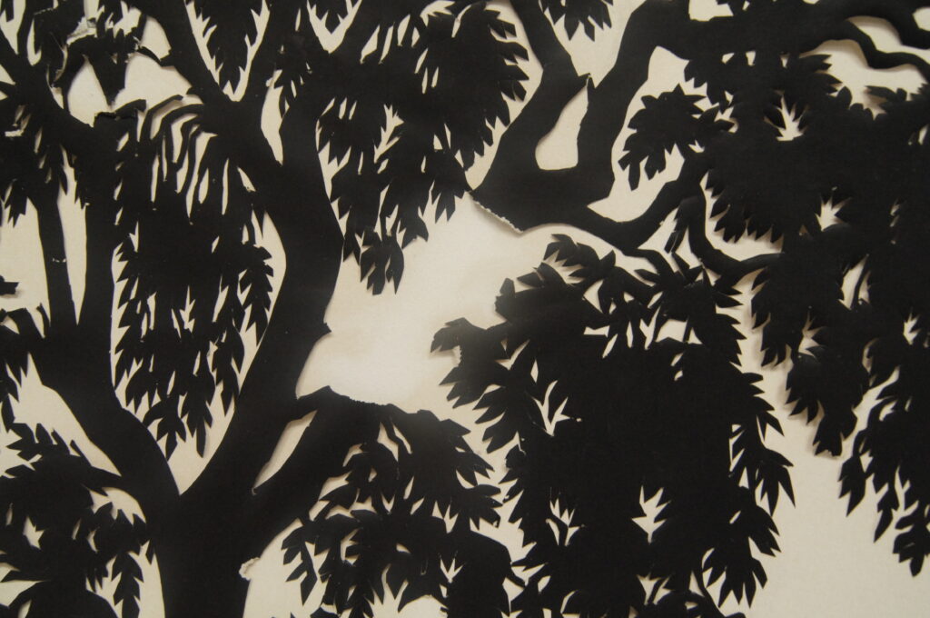 Close up of a papercut of a tree, with part of a branch missing