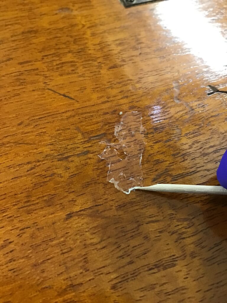 Ellie's hand using a cocktail stick to ease away leftover glue