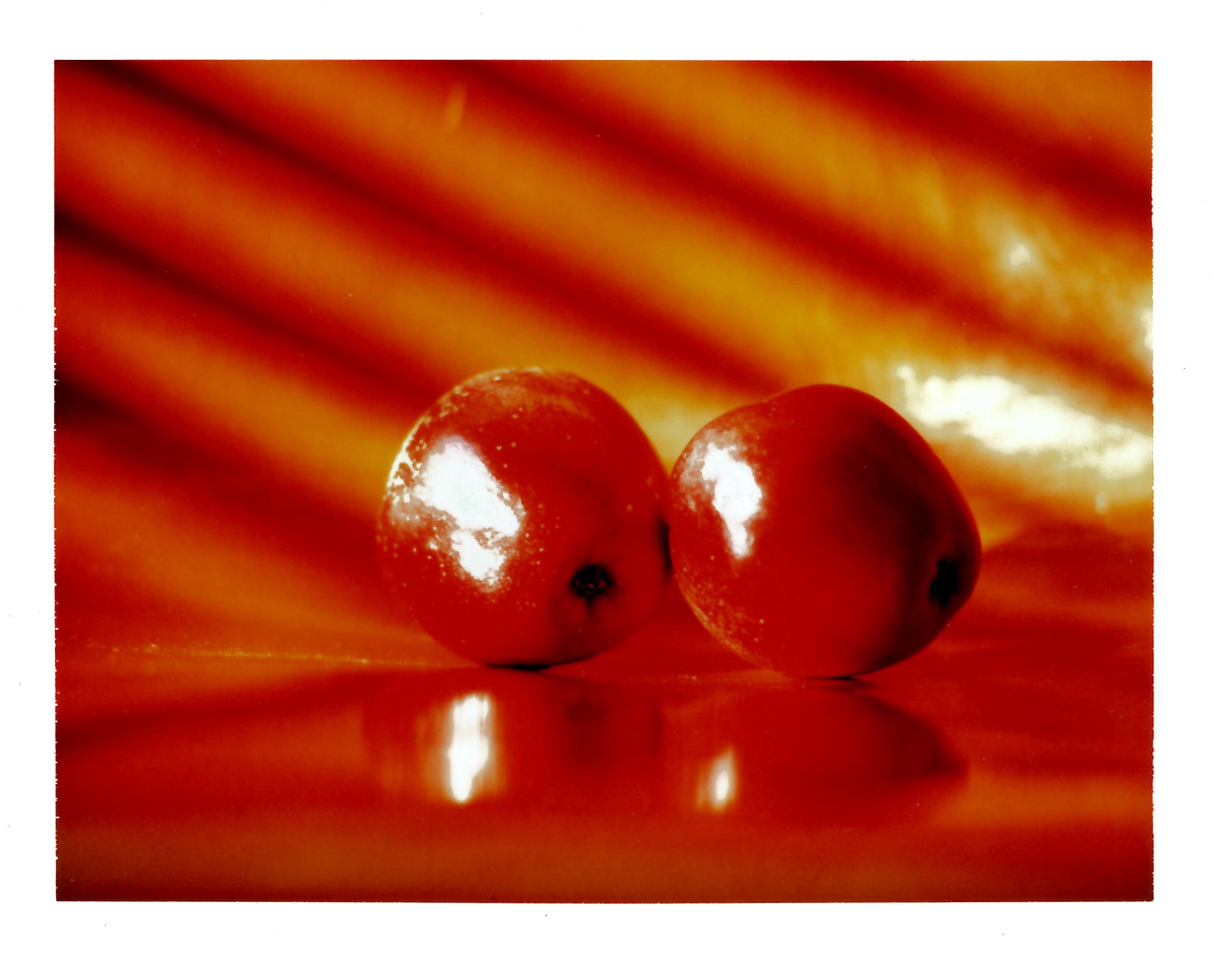 Bright colour photo of two red apples against an orange-red background