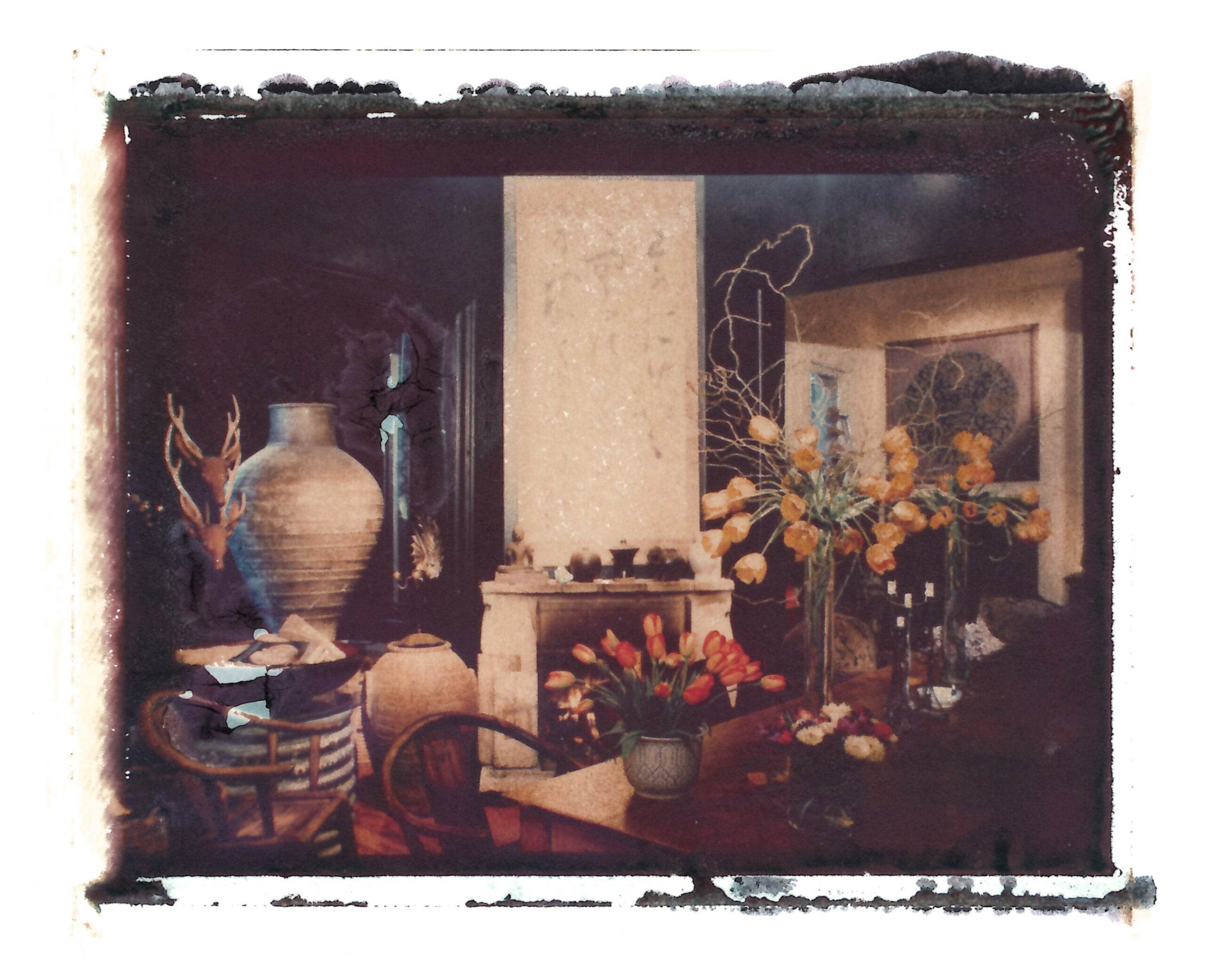 Colour photo of a cluttered room with vases of flowers on a table