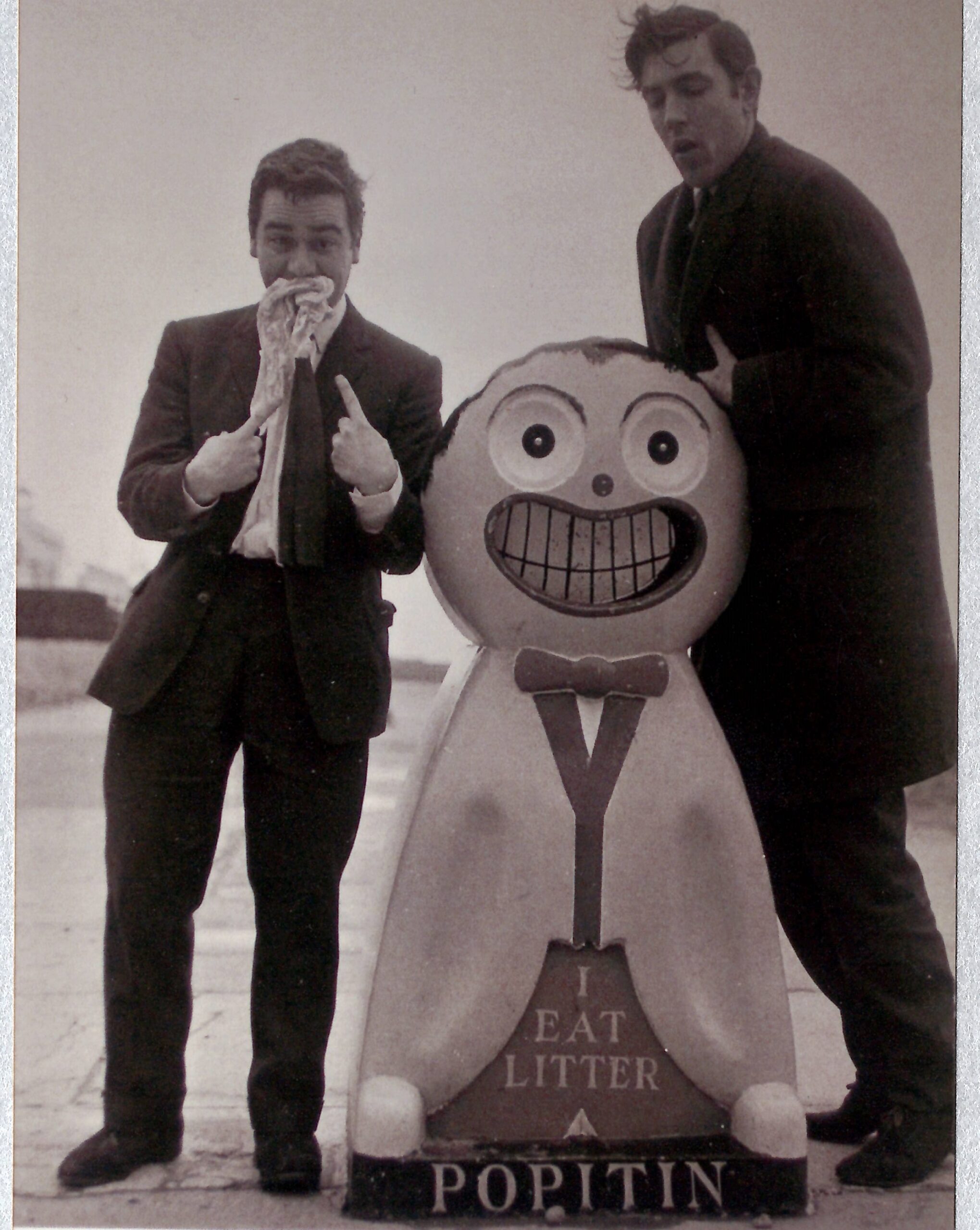 Dudley Moore and Peter Cook posing with a comical person-shaped litter bin