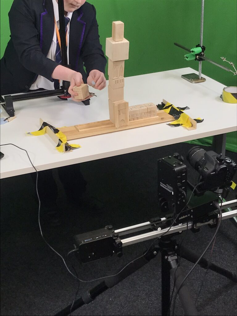 A school pupil building a tower of wooden blocks