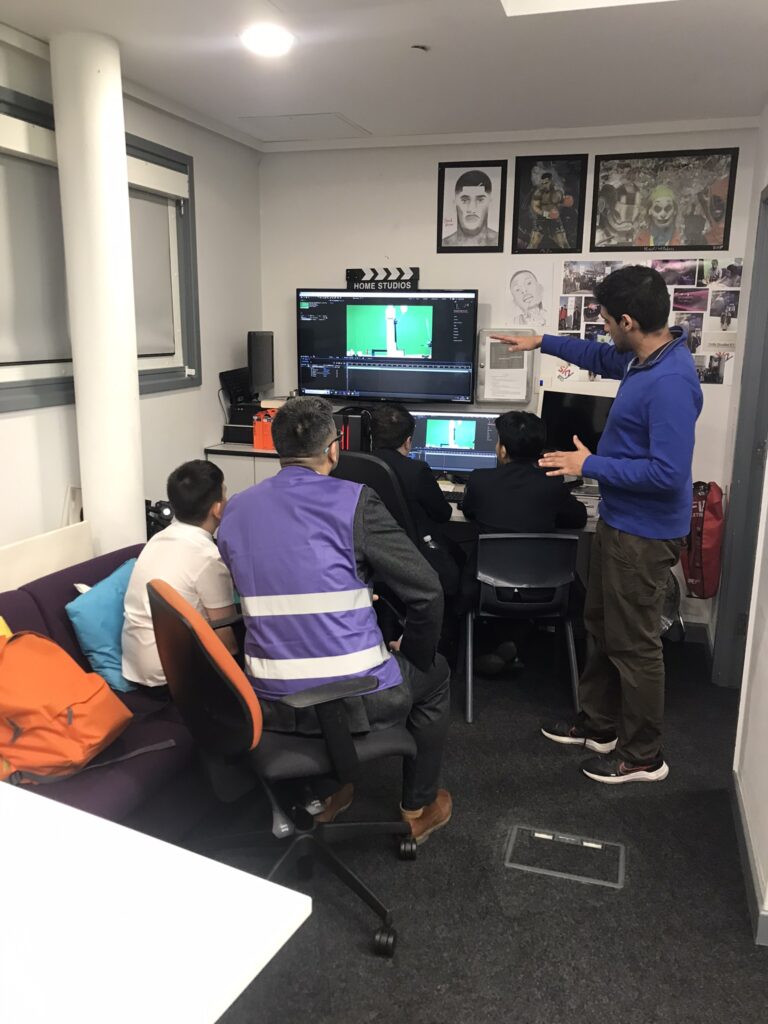 A group of students working at the computer, with Arfaan assisting