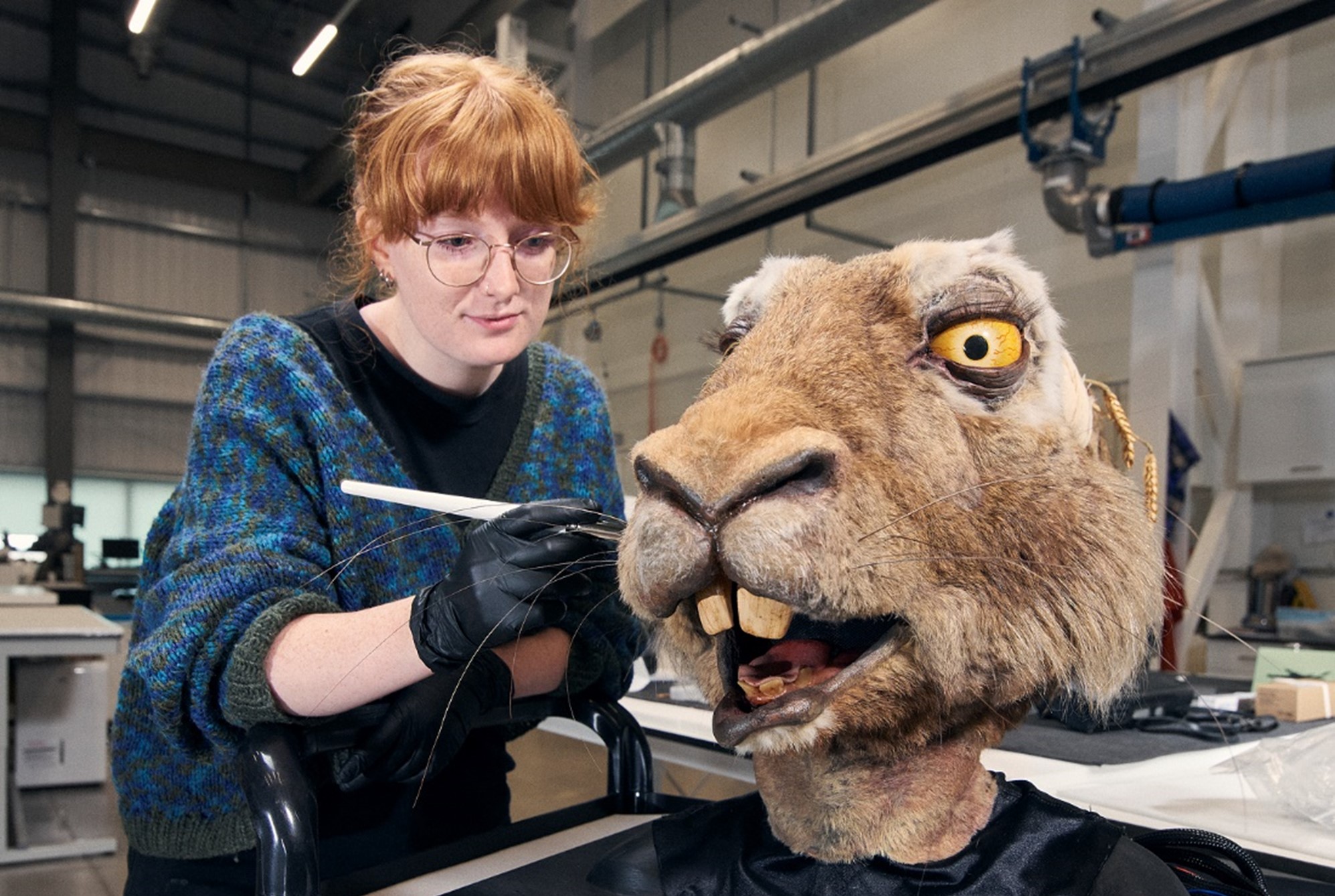 Martha uses a brush on the nose of the hare head in the conservation lab