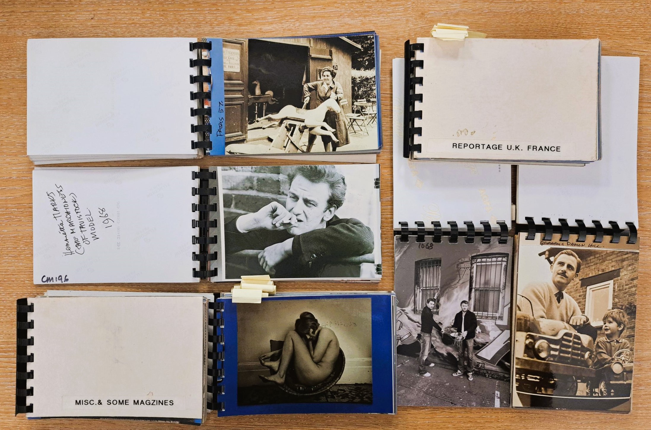 Six postcard size books of photos open on a wooden desktop