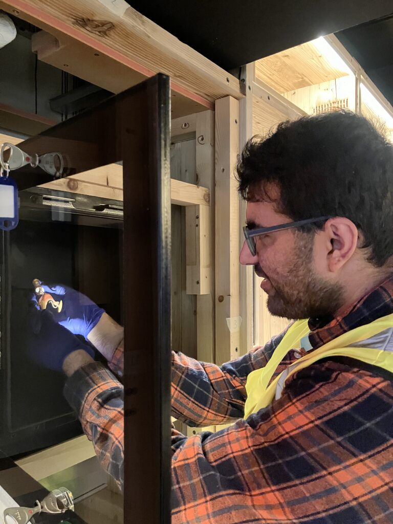 Saquib wears blue nitrile gloves as he places the fangs into a black cabinet