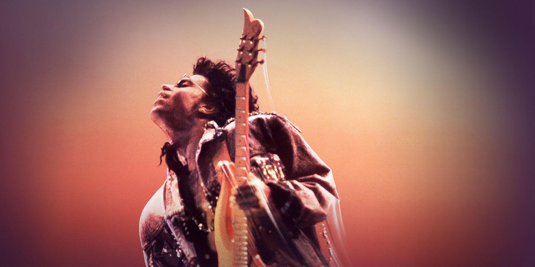 Prince throws his head back as he plays guitar against an abstract pink background