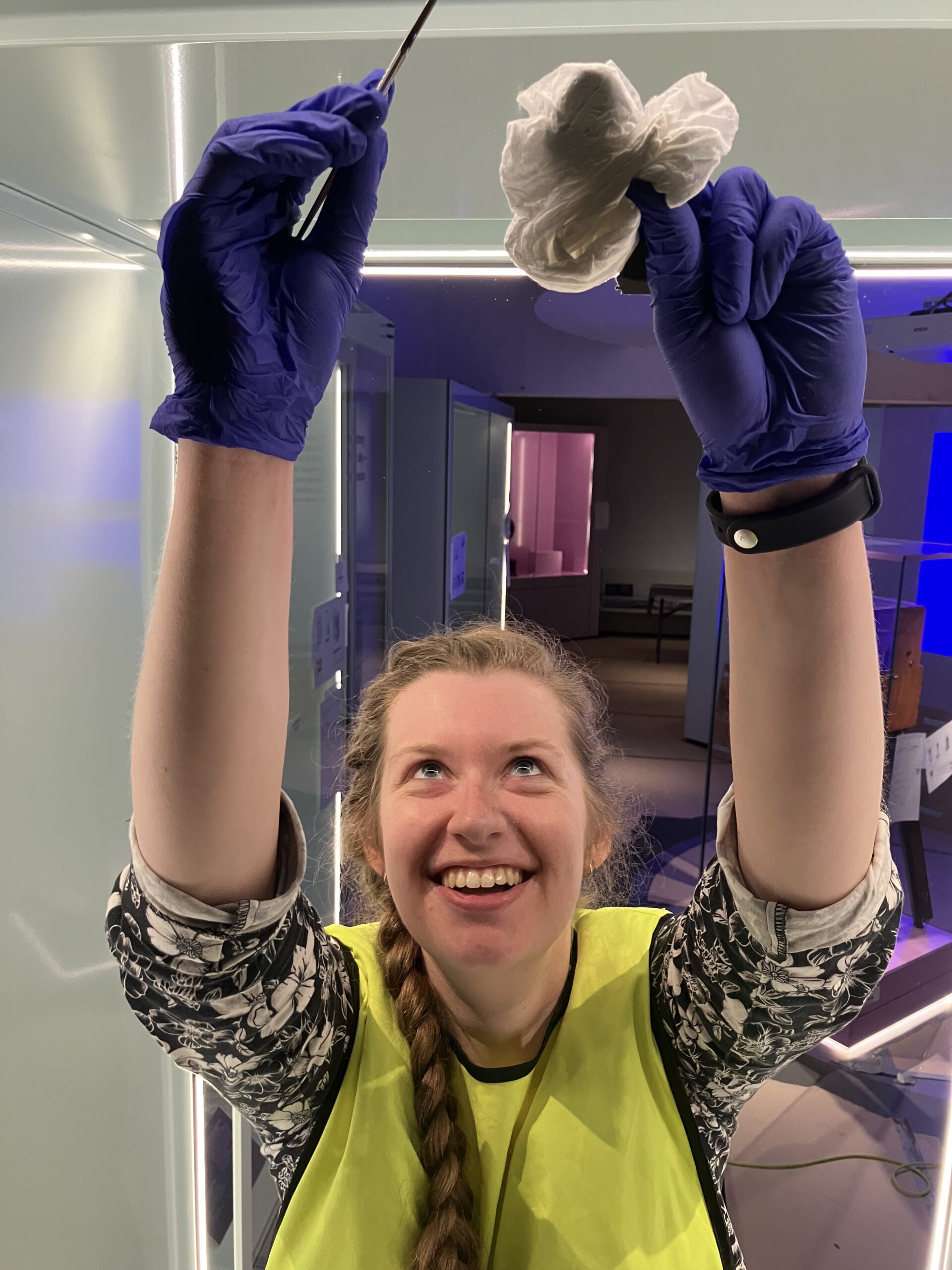 Ellie smiles at she reaches up with tissue and a swab to clean something out of the shot.