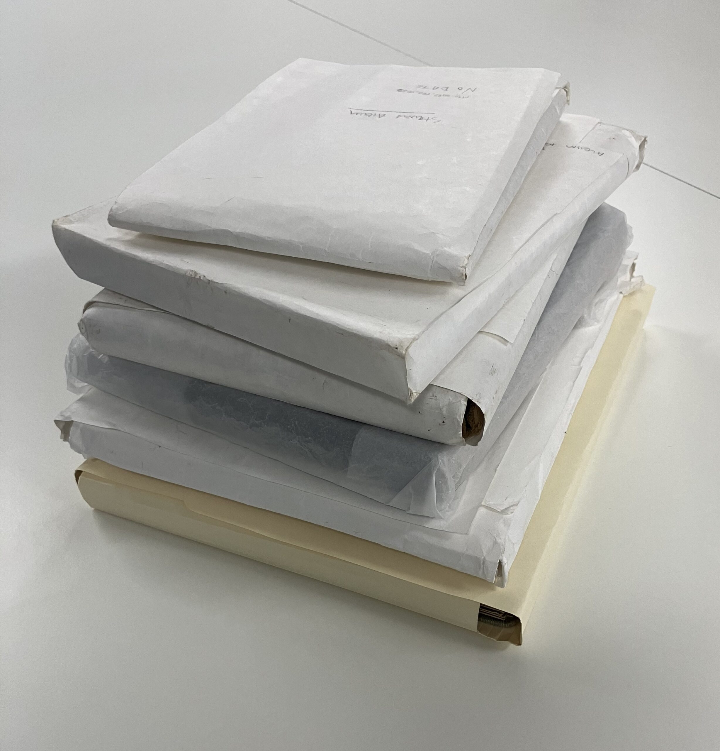 A pile of collection photographs wrapped in various kinds of white tissue paper.