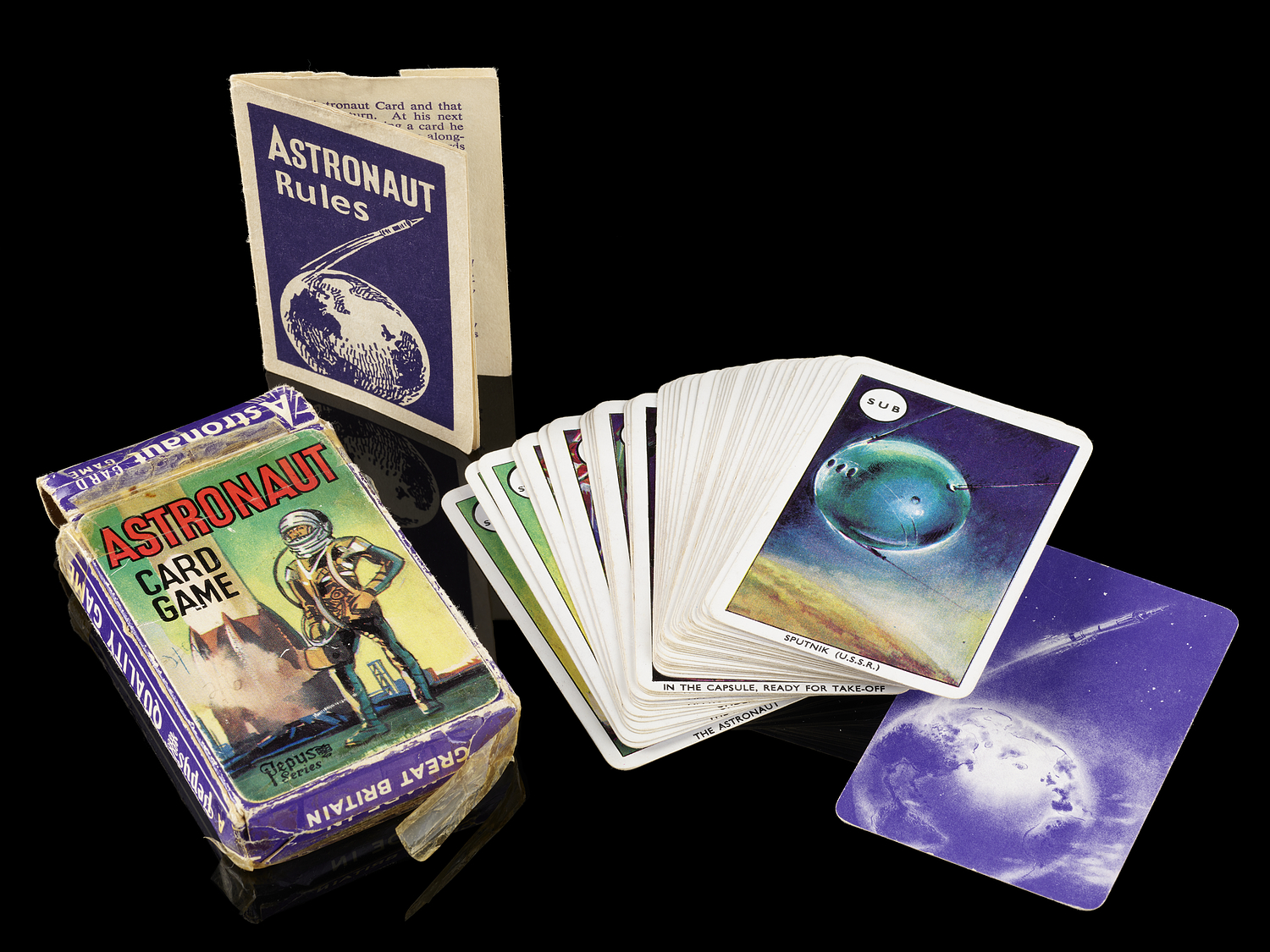 A deck of cards with space-related illustrations, spread out slightly, next to the box and instruction leaflet