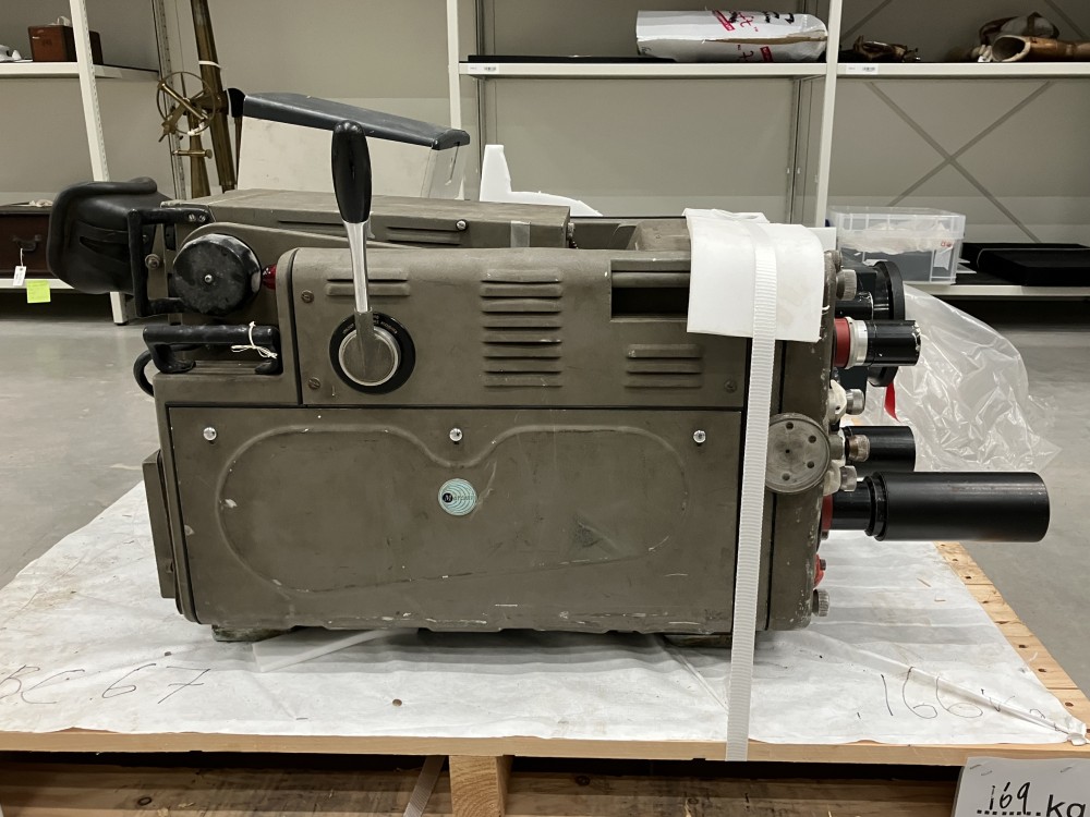 Chunky grey tv camera strapped to a pallet, with signs of corrosion and wear