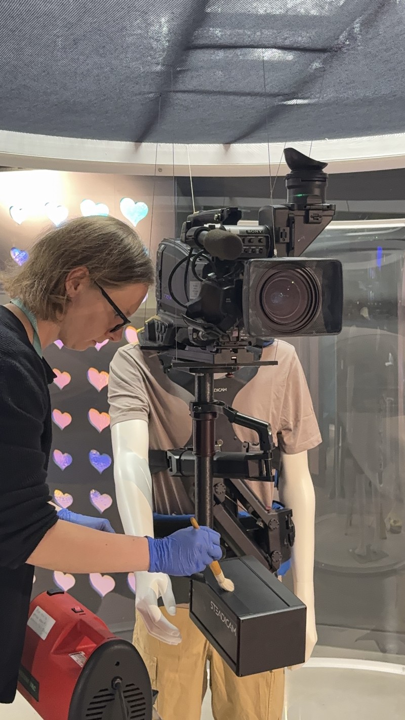 Emma wears blue nitrile gloves and uses a soft brush the clean the object.