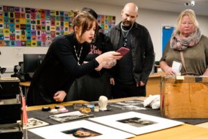 Guests look at a display of Hammer-related objects in Insight; one leans over to take a photo